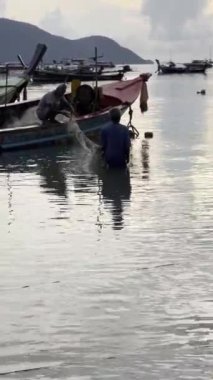 Taylandlı balıkçılar ağ topluyor. Tayland ve günbatımı gökyüzü siluetleri. Dikey HDR 4k video