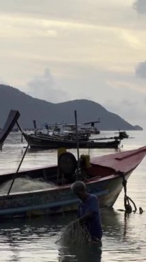 Taylandlı balıkçılar ağ topluyor. Tayland ve günbatımı gökyüzü siluetleri. Dikey HDR 4k video