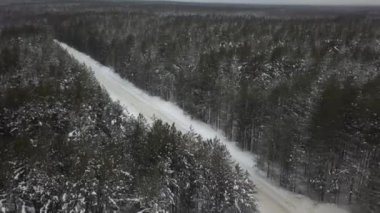 Bir ormanın içinden geçen karlı bir yolun hava manzarası. Su kanalları, şelaleler ve eğimli topraklardaki akıntılı arazilerin doğal bir manzarası.
