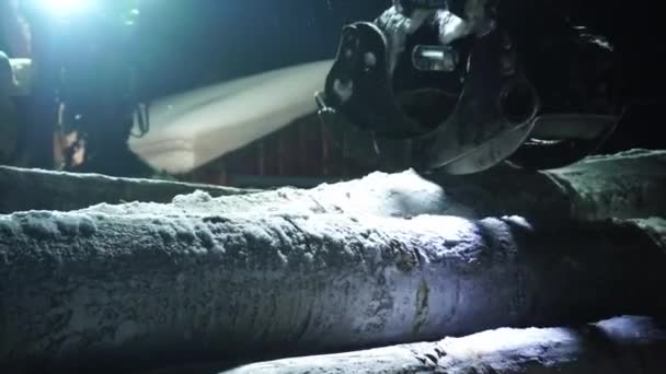 神秘的なビデオは 夜にフォークリフトのスタッキングツリーに男と光が輝いていることを示しています 雪に積まれたログが不気味な雰囲気に加わる — ストック動画