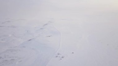 Manzara, arka planda birçok ağaç bulunan kalın bir kar tabakasıyla kaplıdır. Dondurucu soğuklar açık gökyüzüne karşı güzel bir kış manzarası yarattı.