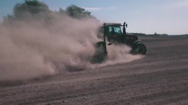 Yuvarlanan otomotiv lastikleri olan traktör bulutlu bir gökyüzünün altındaki toprak bir arazide sürüyor ve güçlü lastik ve tarım mekanizmaları yeteneklerini sergiliyor.