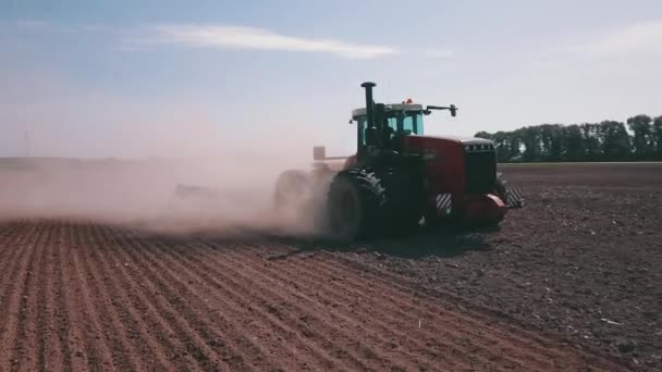 一辆农用汽车正在犁地 产生了一片尘土飞扬的云彩 机器在地里干活时 草地上的天空是清澈的 — 图库视频影像