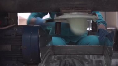 Elektrikli mavi üniformalı bir kadın bir otomotiv etkinliğinde bir otomotiv lastiği makinesinin önünde bir sandalyede oturuyor.