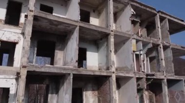 Terk edilmiş bir ev, sayısız penceresi ve berrak mavi bir gökyüzü var.