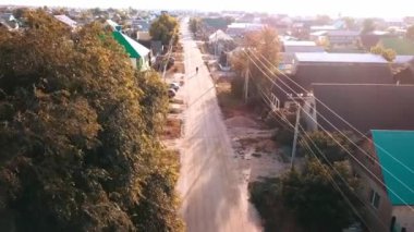 Evleri, virajlı caddeleri ve toprak yolu olan küçük bir kasabanın havadan görünüşü. Huzurlu, kırsal çekiciliği yakalar, sükunet hissi verir.