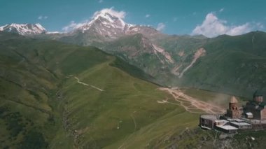Havadan çekilmiş bir video, sakin doğal manzarayla çevrili, yüksek bir dağdaki kiliseyi görüntüler. Bu çarpıcı manzara huzur ve korkuyu çağrıştırıyor.
