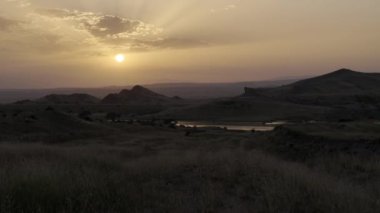 Huzurlu bir günbatımı, yuvarlanan tepeler ve huzurlu bir nehir üzerine ılık bir parıltı saçar, güzellikleri gözler önüne serer.