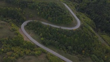 Hava perspektifi, yemyeşil ve manzaralı tepelerde zarifçe kıvrılan güzel kıvrımlı bir yolu sergiliyor.