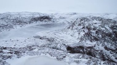 Bu hava manzarası, donmuş göller ve engebeli dağ zirveleriyle göz kamaştırıcı bir kar manzarası sergiliyor. Arctic Village Teriberka, Kola Yarımadası, Rusya. Şelale