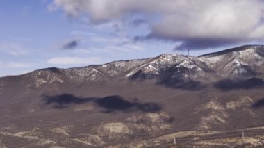 Göz kamaştırıcı kar örtülü dağ sırasının nefes kesen manzarası dramatik, girdap gibi dönen bulutlarla tamamlanır.