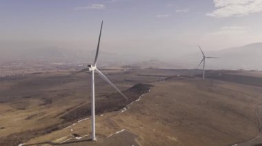 Georgias arazisindeki rüzgar türbinlerinin hava manzarası, dağları ve araziyi gösteriyor.