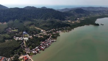 Çarpıcı bir insansız hava aracı görüntüsü, Tayland 'da bir kıyı köyünü gösteriyor. Dağlar ve sakin su tarafından çerçevelenmiş.