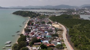 Bir hava aracı görüntüsünde büyüleyici suları ve yeşilliği olan pitoresk bir Tayland kıyı köyü sergileniyor.
