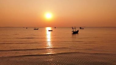 Güzel Tayland 'da balıkçı tekneleriyle okyanusun üzerinde çarpıcı bir günbatımının tadını çıkarıyorum.
