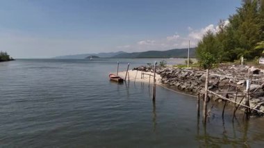 Manzaralı bir drone manzarası bir nehir kıyısı, kayalık bir kıyısı ve uzak dağları gösteriyor..