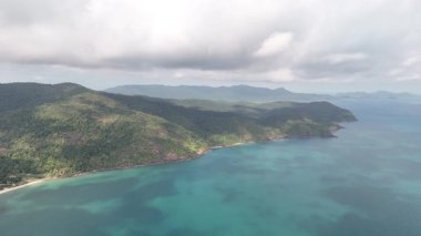 Bir hava görüntüsü, yemyeşil ve açık mavi suların yer aldığı Tayland kıyı şeridini gösteriyor.