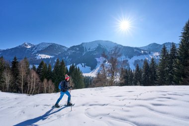 Oberstaufen ve Steibis, Bavyera, Almanya yakınlarındaki Allgau Alpleri 'nin dağlarında, Hochgrat Dağı' nın altında kar altında kar altında kar ayakkabısı giyen hoş ve aktif son sınıf öğrencisi bir kadın.