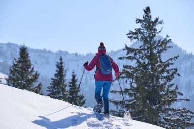 Oberstaufen ve Steibis, Bavyera, Almanya yakınlarındaki Allgau Alpleri 'nin dağlarında, Hochgrat Dağı' nın altında kar altında kar altında kar ayakkabısı giyen hoş ve aktif son sınıf öğrencisi bir kadın.