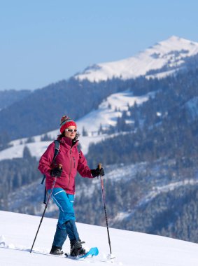 Oberstaufen ve Steibis, Bavyera, Almanya yakınlarındaki Allgau Alpleri 'nin dağlarında, Hochgrat Dağı' nın altında kar altında kar altında kar ayakkabısı giyen hoş ve aktif son sınıf öğrencisi bir kadın.