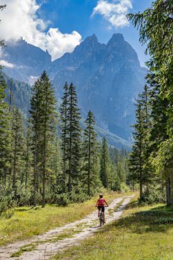 Arka planda Sexten Dolomites nükteli Fischlein Vadisi 'nde bisiklete binen son sınıf güzel bir kadın, Tre cime Ulusal Parkı, Güney Tirol, İtalya 