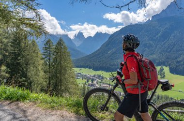 Arka planda Sexten Dolomites nükteli Fischlein Vadisi 'nde bisiklete binen son sınıf güzel bir kadın, Tre cime Ulusal Parkı, Güney Tirol, İtalya 