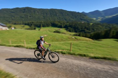 Steibis, Bavyera, Almanya yakınlarındaki Allgau ve Bregenz Ormanları 'nın muhteşem manzarasının tadını çıkaran, elektrikli dağ bisikletine binen son sınıf güzel bir kadın.