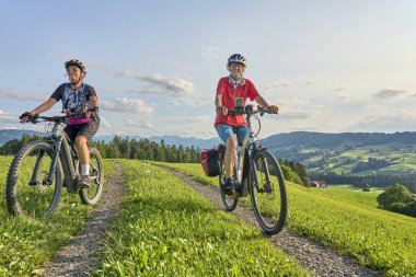 Avusturya, Vorarlberg, Sibratsgfll yakınlarındaki Bregenz Ormanı 'nda bisiklet turunda eğlenen iki son sınıf öğrencisi kız arkadaş.