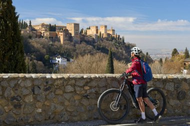 Alhambra, Granada, Granada, Endülüs, İspanya 'daki dünya mirası sahasının altında elektrikli dağ bisikletiyle bisiklet süren hoş, aktif bir son sınıf öğrencisi.,