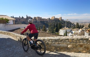 Alhambra, Granada, Granada, Endülüs, İspanya 'daki dünya mirası sahasının altında elektrikli dağ bisikletiyle bisiklet süren hoş, aktif bir son sınıf öğrencisi.,