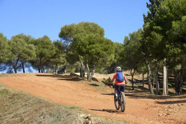 Granada, Endülüs, İspanya yakınlarındaki çam ağaçları ormanlarında elektrikli dağ bisikletine binen hoş, aktif yaşlı bir kadın.