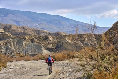 Almeria, Andlusia, İspanya yakınlarındaki Tabernas çölünde, elektrikli dağ bisikletiyle gezen hoş, aktif, son sınıf öğrencisi bir kadın.
