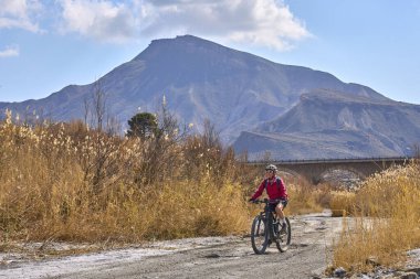 Almeria, Andlusia, İspanya yakınlarındaki Tabernas çölünde, elektrikli dağ bisikletiyle gezen hoş, aktif, son sınıf öğrencisi bir kadın.