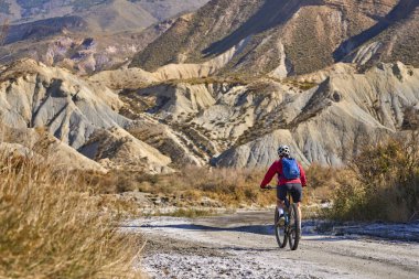 Almeria, Andlusia, İspanya yakınlarındaki Tabernas çölünde, elektrikli dağ bisikletiyle gezen hoş, aktif, son sınıf öğrencisi bir kadın.