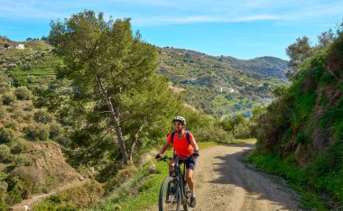 Nerja, Endülüs, İspanya yakınlarındaki Sierra de Tejada 'da elektrikli dağ bisikletiyle bisiklet süren hoş bir kadın.