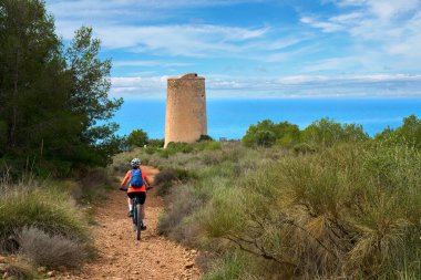 İspanya, Endülüs, Nerja yakınlarındaki Costa Blanca sahil şeridinde son sınıf öğrencisi güzel bir bayan elektrikli dağ bisikletiyle bisiklet sürüyor.