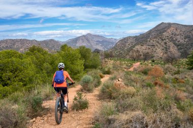 İspanya, Endülüs, Nerja yakınlarındaki Costa Blanca sahil şeridinde son sınıf öğrencisi güzel bir bayan elektrikli dağ bisikletiyle bisiklet sürüyor.