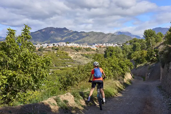 İspanya 'nın Endülüs kenti Nerja yakınlarındaki Frigiliana beyaz köyünde elektrikli dağ bisikletiyle bisiklet süren hoş bir son sınıf öğrencisi.