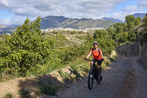 İspanya 'nın Endülüs kenti Nerja yakınlarındaki Frigiliana beyaz köyünde elektrikli dağ bisikletiyle bisiklet süren hoş bir son sınıf öğrencisi.