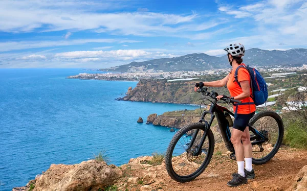 İspanya, Endülüs, Nerja yakınlarındaki Costa Blanca sahil şeridinde son sınıf öğrencisi güzel bir bayan elektrikli dağ bisikletiyle bisiklet sürüyor.