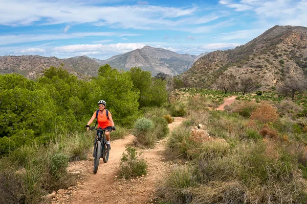 İspanya, Endülüs, Nerja yakınlarındaki Costa Blanca sahil şeridinde son sınıf öğrencisi güzel bir bayan elektrikli dağ bisikletiyle bisiklet sürüyor.