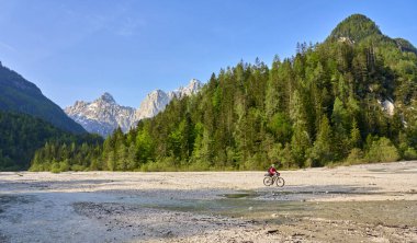 Slovenya 'daki Triglav Ulusal Parkı' nda elektrikli dağ bisikletiyle Soca Nehri boyunca bisiklet turunda olan hoş bir kadın. 
