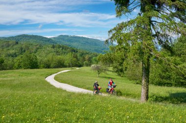 Slovenya 'nın Kobarid kenti yakınlarındaki Triglav Ulusal Parkı' ndaki River Soca Vadisi 'nde bisiklet turunda aktif kıdemli bir çift.