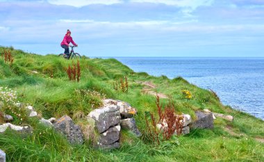 İrlanda 'nın kuzeyinde Malin Beg Head, Donegal tepelerinde bisiklete binen son sınıf öğrencisi hoş bir kadın.