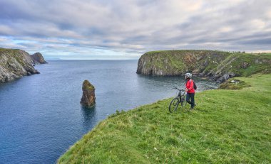 İrlanda 'nın kuzeyinde Malin Beg Head, Donegal tepelerinde bisiklete binen son sınıf öğrencisi hoş bir kadın.