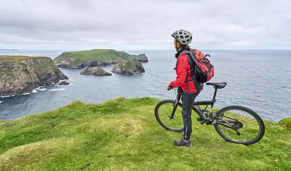 İrlanda 'nın en kuzeyindeki Malin Head kayalıklarında bisiklete binen son sınıf öğrencisi hoş bir kadın.