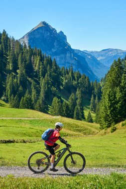 woman riding her electric mountain bike on the Stoggersattel in the  Bregenz Forest Mountains near near village of Au, Vorarlberg, Austria