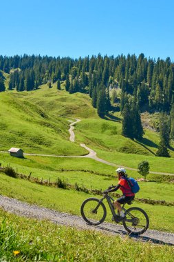 woman riding her electric mountain bike on the Stoggersattel in the  Bregenz Forest Mountains near near village of Au, Vorarlberg, Austria