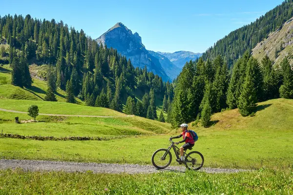 woman riding her electric mountain bike on the Stoggersattel in the  Bregenz Forest Mountains near near village of Au, Vorarlberg, Austria