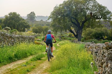 active senior woman cycling with her electric mountain bike in the rough landscape of National Parc Serra de So Mamede near Marvao in central Portugal, Europe